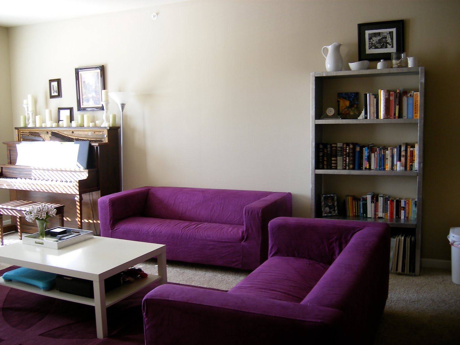 Menggunakan pop warna ungu dengan memadankan set sofa ungu dengan dinding ruang tamu lembut