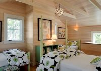 Bilik tidur dinding kayu ini dihiasi dengan selimut cadar dan sarung bantal hijau putih